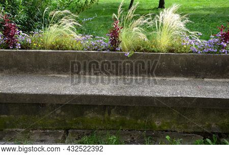 On The Edge Of The Elevated Terrace Overlooking The Park Is A Concrete Long Flowerpot With A Concret