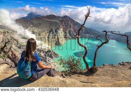 Woman Traveler At  Crater Of Active Volcano Ijen And Dead Tree, Java Island, Indonesia
