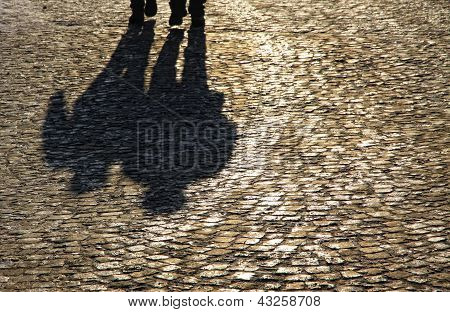 Obrysy a stíny lidí, kteří jdou na cihlové dlažbě