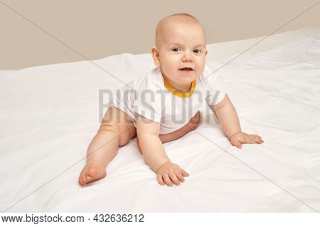 Cute Small Boy Sitting At House. Childhood Concept. Light Background. Smiling Child. Happy Emotion. 