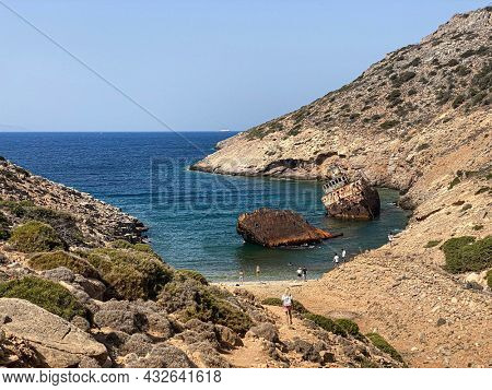 People on the beach visiting Shipwreck Olympia boat in Amorgos island during summer holidays, at the coastal rocky area, , Cyclades, Greece. Travel background