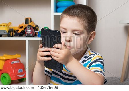 A Little Boy 3-4 Years Old Looks Into The Phone Screen. Cartoons For Children, Screen Time, Children