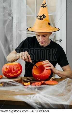 Man Curving Jac O Lanten Helloween Pumpkin At Home. Getting Ready For The Holiday,