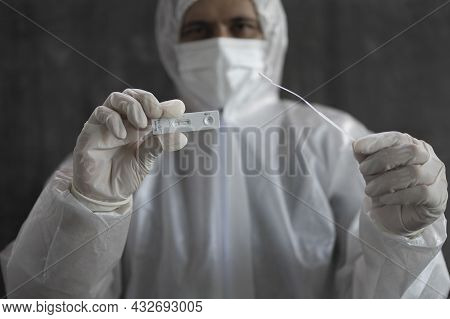 Front Medical Personnel In Personal Protective Equipment (ppe) Suit Holding Antigen Test Kit (atk)