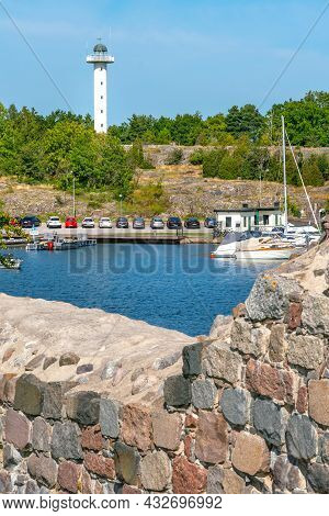 Vastervik, Sweden - 08.22.2021: White Slim Building Of Lighthouse With Bay In Front On A Sunny Summe