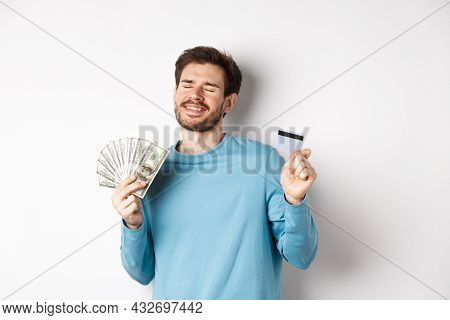 Cheerful Guy Celebrating Salary, Dancing With Plastic Credit Card And Money, Smiling Satisfied, Stan
