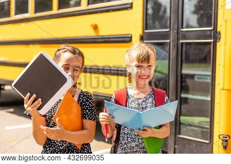 Cheerful Little Girls Next To School Bus. Backback. Back To School Concept.