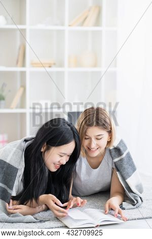Friendly Homework. Happy Female Friends. Home Education. Pretty Smiling Asian Caucasian Women Laying