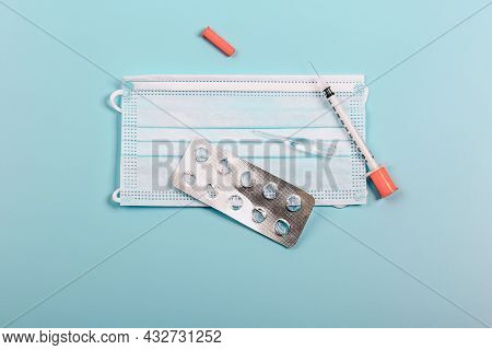 Health Protection And Medicine. Medical Mask, Blister Of Pills, Ampoule, Syringe On A Blue Backgroun