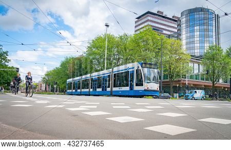 Amsterdam Netherlands - August 20 2017; Cyclists And Train Cross Intersection In City Together