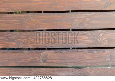 Fragment Of Fencing Built Of Wooden Planks Not Tightly Adjacent To Each Other, Covered With Mordant,