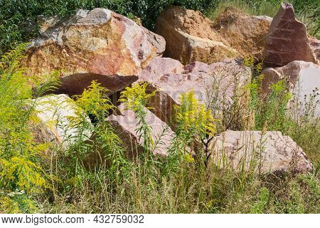 Large Blocks Of Red Granite With Torn Edges With Marks Of Imploding Works Lie Among Flowering Grass 