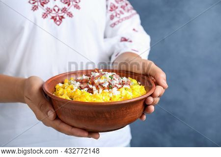 Woman Holding Bowl Of Banosh With Brynza And Pork Cracklings On Blue Background, Closeup. Traditiona