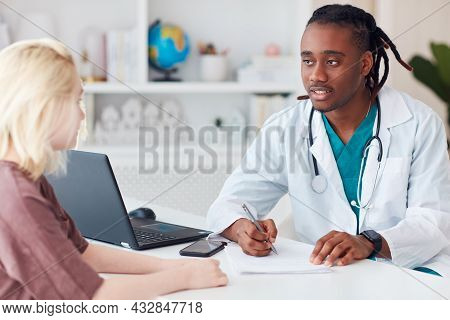 Positive African American Doctor With Tracheostomy Scar Talking With Young Patient At The Office