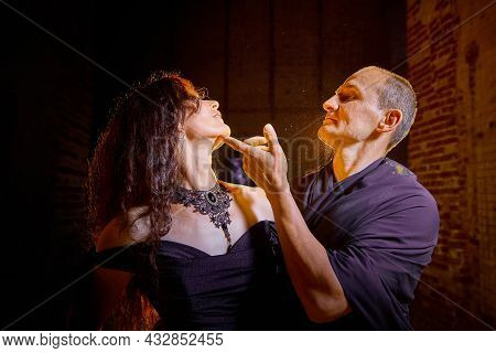 A Couple In Old Dark Clothes In An Abandoned Castle With Old Brick Walls. A Man And A Woman Posing I