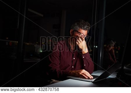 Tired Middle Age Businessman Rubbing His Eyes While Sitting In Front Of Laptop Computer Working On P