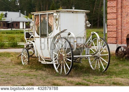 Old White Carriage On The Background Of A Red Brick Building