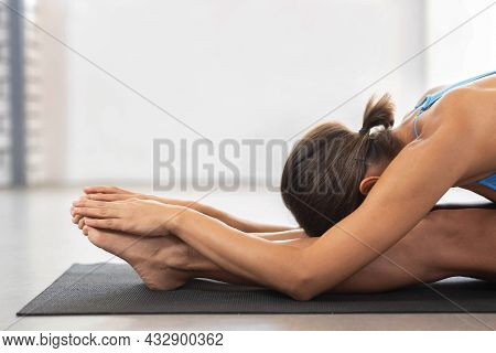 Brunette Woman Doing Stretching Workout Exercises While Sitting On The Floor, Yoga