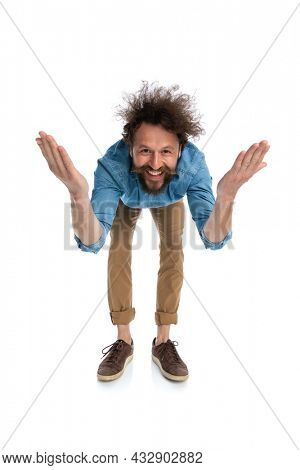 casual handsome man leaning forward with open arms against white background