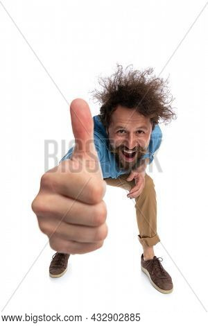 attractive casual man leaning forward and giving a thumbs up against white background