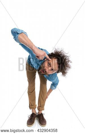 attractive casual man leaning forward and pointing at his head on white background