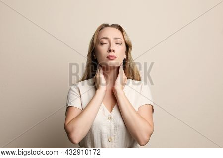Young Woman Doing Thyroid Self Examination On Beige Background