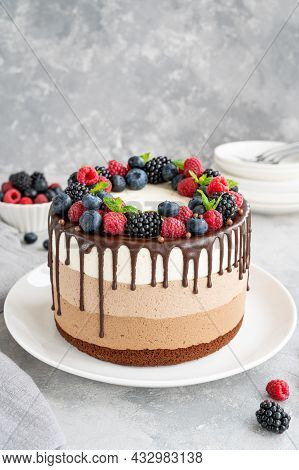 Three Chocolate Mousse Cake With Chocolate Glaze, Blueberries, Raspberries And Blackberries On Top O