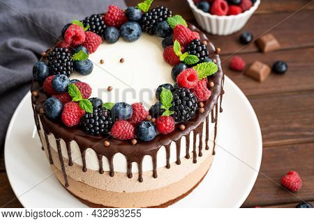 Three Chocolate Mousse Cake With Chocolate Glaze, Blueberries, Raspberries And Blackberries On Top O