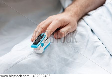 Male Hands With A Pulse Oximeter On The Index Finger, Close-up. A Hospitalized Patient Is In The Hos