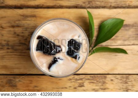 Glass Of Milk With Grass Jelly And Green Leaves On Wooden Table, Flat Lay