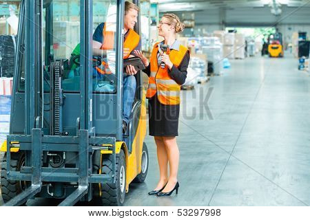Logistics Teamwork - forklift driver, Worker or warehouseman and his coworker with scanner at warehouse of freight forwarding company