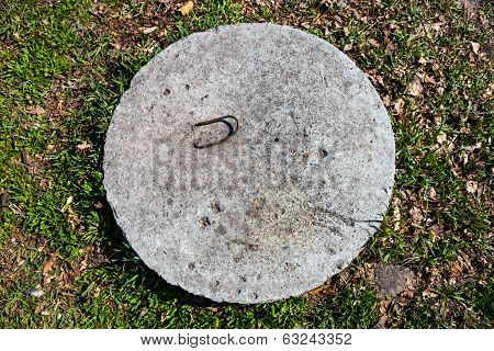 Concrete manhole cover in the grass