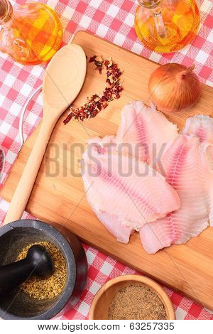 Raw fish tilapia on cutting board and spices