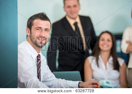 Smling businessman sitting in office posing