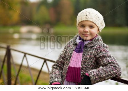 relaxační milá dívka v bílém baretu a podzimní kabát poblíž řeky