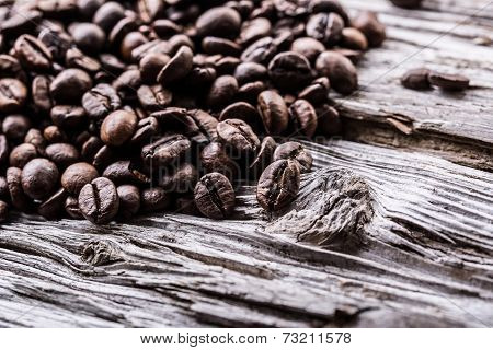 Spilled coffee beans on a very old wooden table.