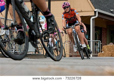 Low-angle Perspective Of Female Cyclists Racing Into Turn