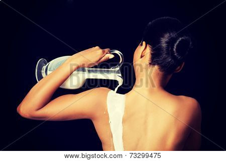 Nude woman is holding a ewer or yug of milk. Spa concept.
