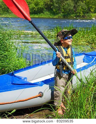 Boy near a kayak on the river
