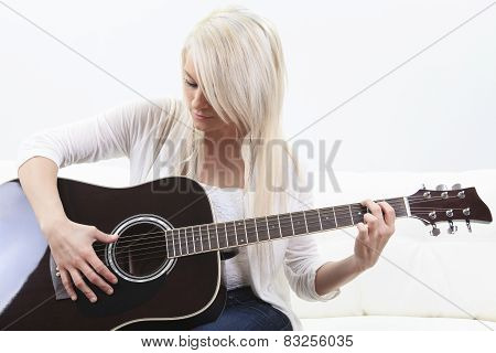 beautiful young woman on the couch with a guitar