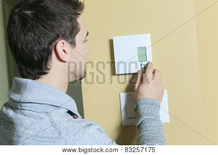 A man set the thermostat at house.