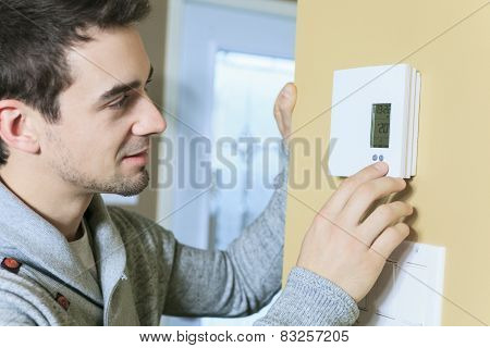 A man set the thermostat at house.
