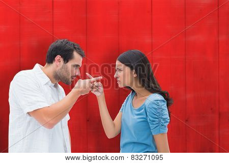 Angry couple pointing at each other against red wooden planks