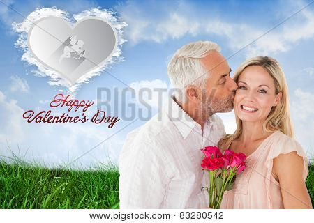 Affectionate man kissing his wife on the cheek with roses against cloud heart