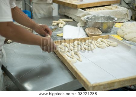 Bakers Making Fresh Pretzels On Dough Covered Table