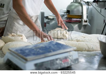 Baker Tossing Flour On Raw Dough