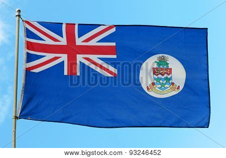 Flag of the Cayman Islands against blue sky. Cayman Islands is British Overseas Territories. The national flag is described as British blue ensign with the arms on a white disc in the flag.