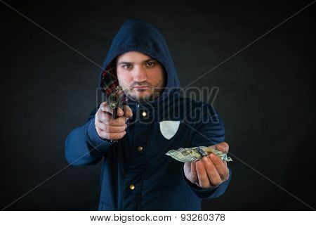 A Person In A Hoodie Is Aiming And Holding The Other Hand With The Dollar Note. A Concept Of The Rob