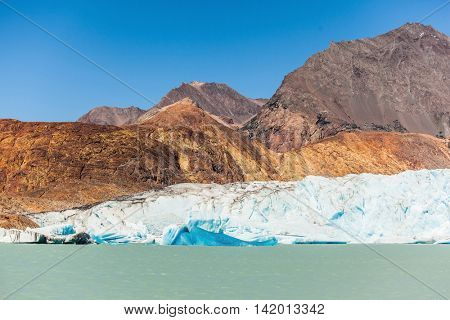 Unique lake Viedma in Patagonia. The enormous glacier sliding into the lake. From the edge of the glacier break off huge blue floes. Pleasure tourist boat floats to the glacier