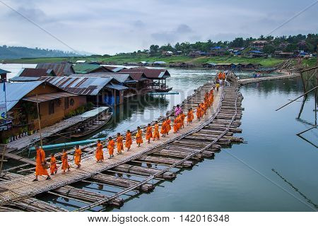 KANCHANABURI ,THAILAND - APRIL 18 2014: Buddhist monks walk on Bamboo Bridge the Sangkhla Buri River, Kanchanaburi, Thailand.